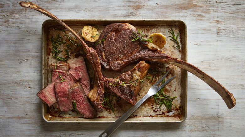 whole and slice tomahawk steak on roasting pan