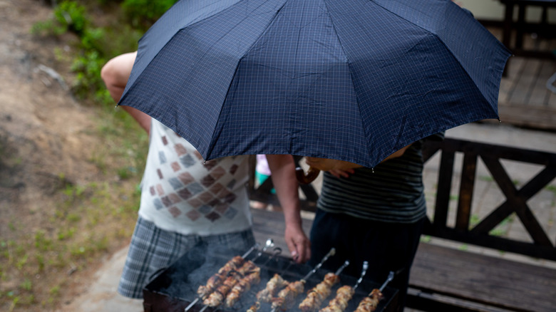 man at grill under umbrella 