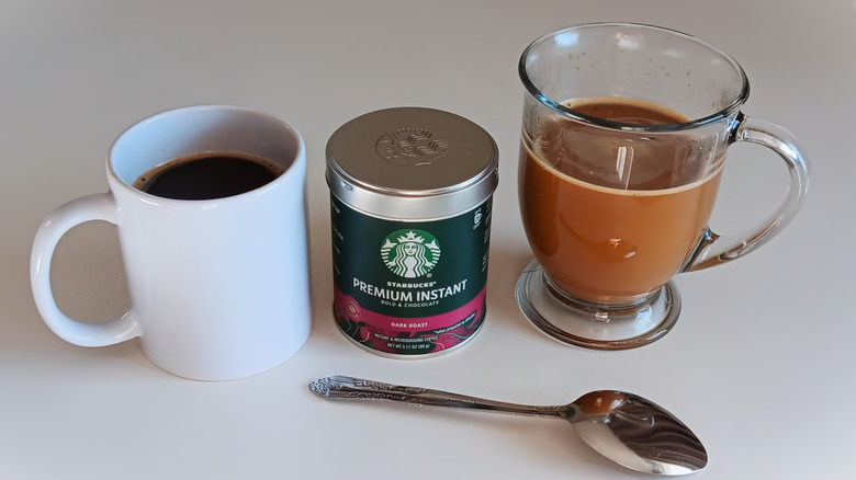 Starbucks instant coffee canister with mugs of coffee, black and cream