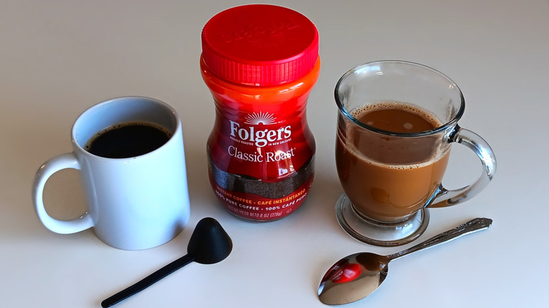 Folgers instant coffee jar with mugs of coffee, black and with cream