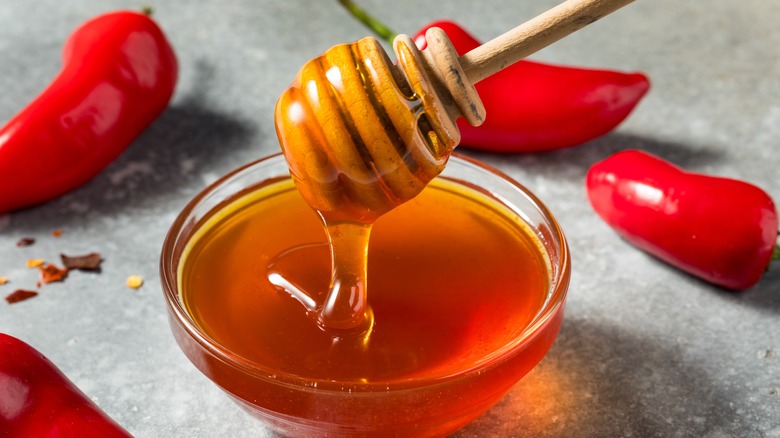 spicy hot honey and peppers in a bowl with dipper