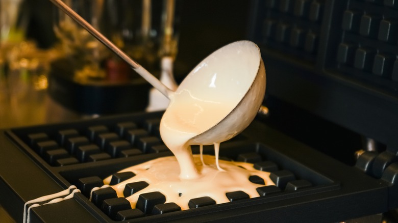 waffle bater poured into waffle maker in kitchen at home