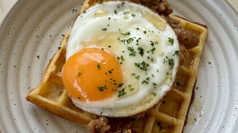 serving of chicken and waffles, topped with a fried egg