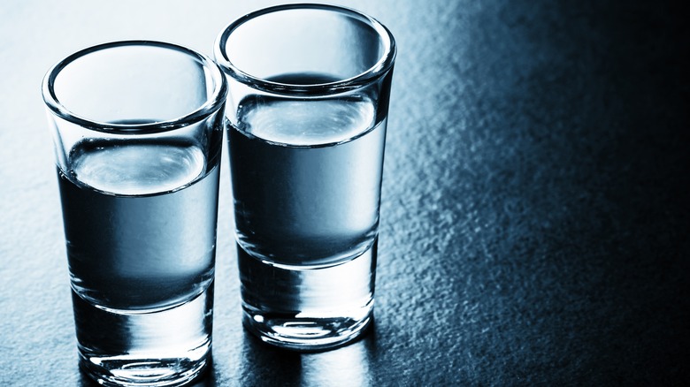 Two shot glasses filled with on a dark gray counter