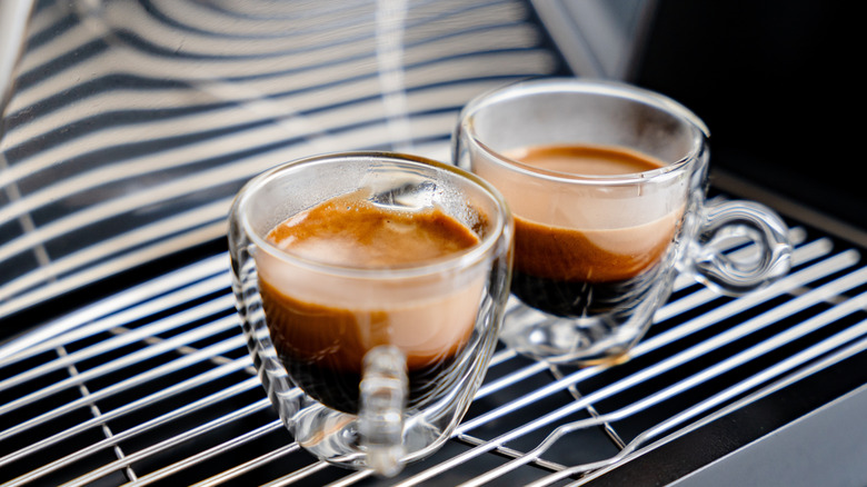 Two glass cups of espresso standing on an espresso machine