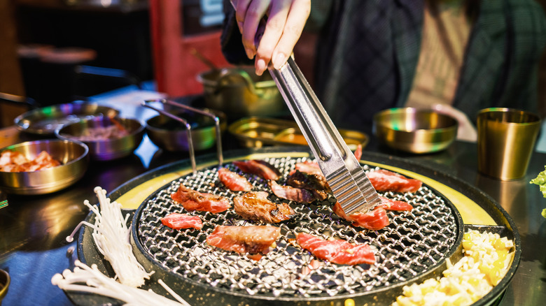 Tongs turning meat on a grill