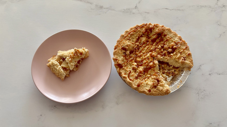An apple caramel pie sitting next to a slice of pie on a plate.