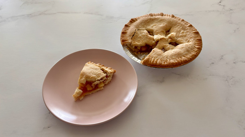 An apple pie sitting on a counter next to a plate.