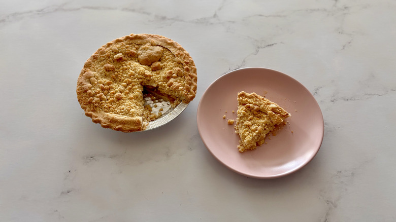 A Dutch apple pie sitting next to a plate.