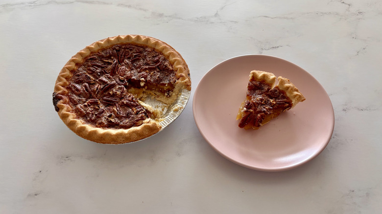 A pecan pie placed next to a plate.