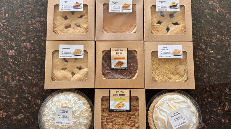 Various Walmart pies sitting in boxes on a countertop.