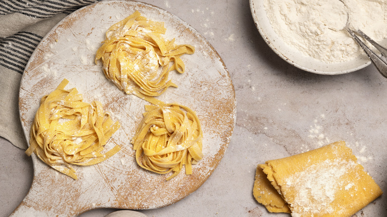 Fresh coiled noodles beside flour