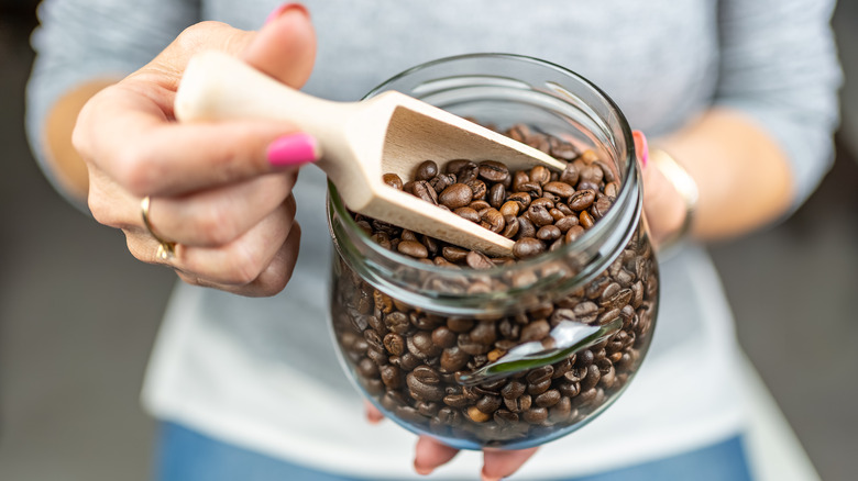 woman scoops coffee beans