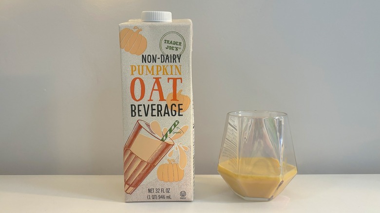 Box and glass of Trader Joe's Non-Dairy Pumpkin Oat Beverage on white background