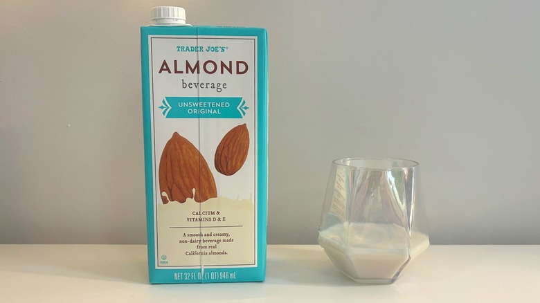 Box and glass of Trader Joe's Unsweetened Original Almond Beverage on white background