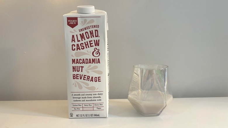 Box and glass of Trader Joe's Unsweetened Almond, Cashew, & Macadamia Nut Beverage on white background