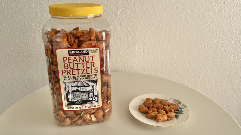 Plastic container of Kirkland peanut butter pretzel bites next to plate of pretzel bites