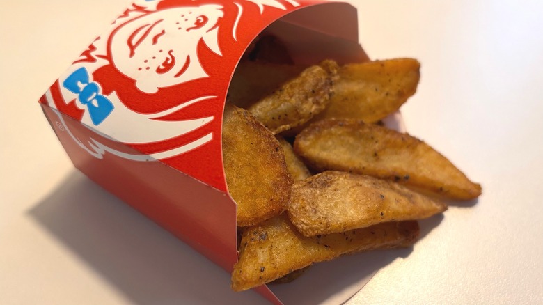 Container of Wendy's seasoned potatoes on white table