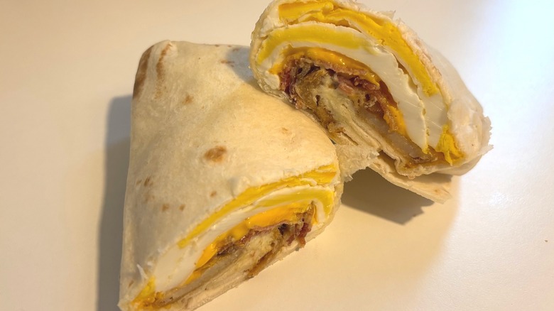 Wendy's Bacon Breakfast Burrito cut in half on white table