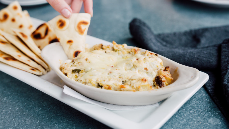 Hand dipping bread in dip