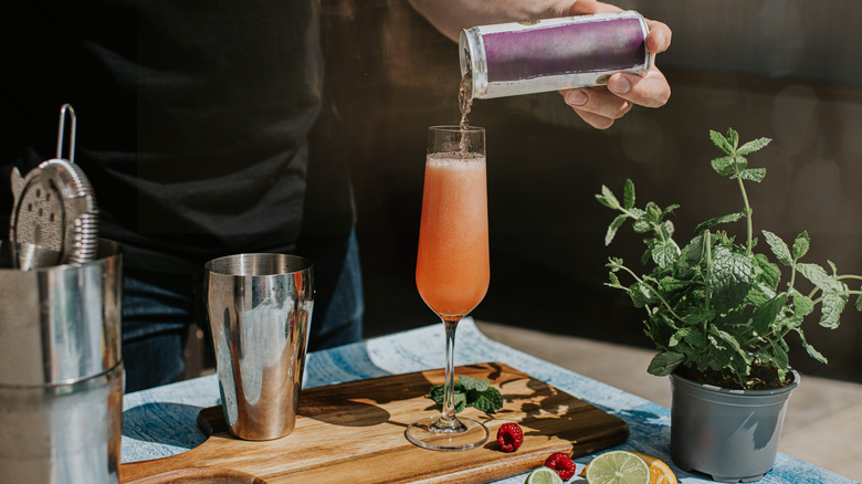 Hand pouring can into cocktail glass