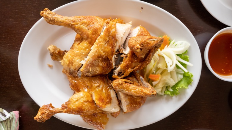 Whole fried chicken on white plate