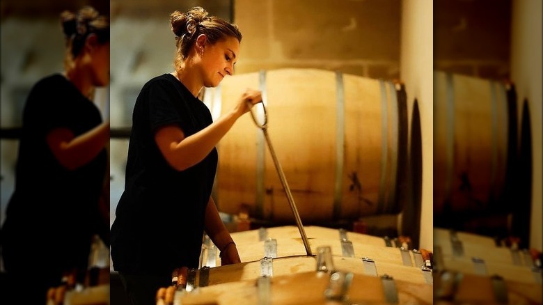 winemaker stirring barrel lees