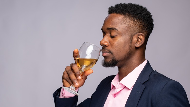 man in suit smelling wine