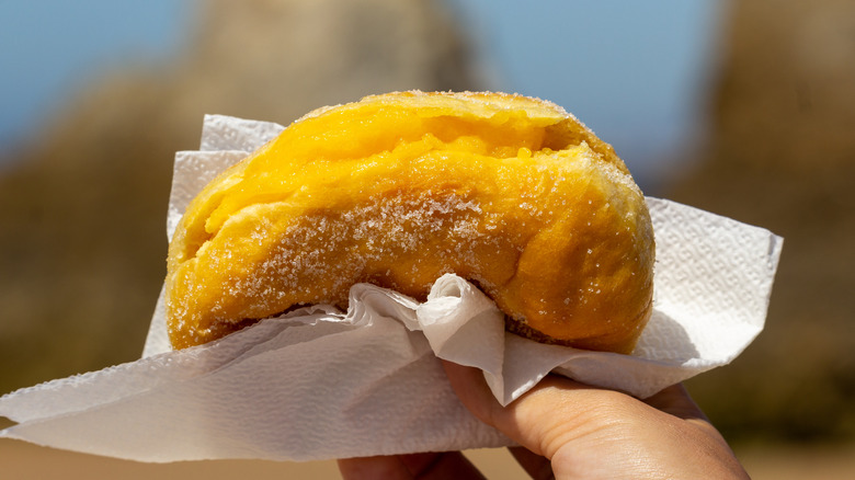 Hand holding filled donut in napkin 