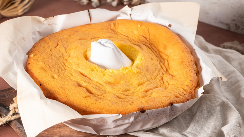 Sponge cake resting in paper-covered pan