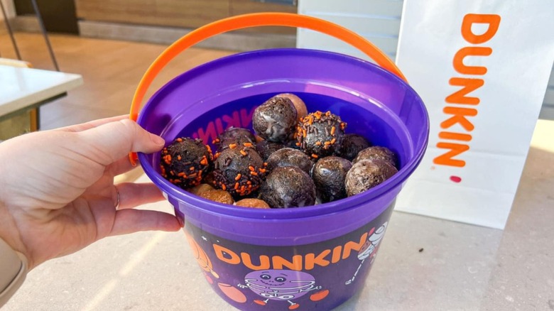 Hand holding purple bucket full of Munchkins on table