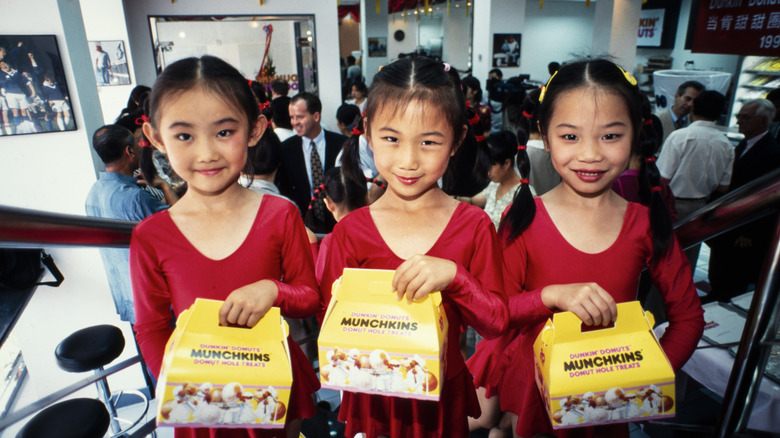 Three children holding Munchkins box in restaurant