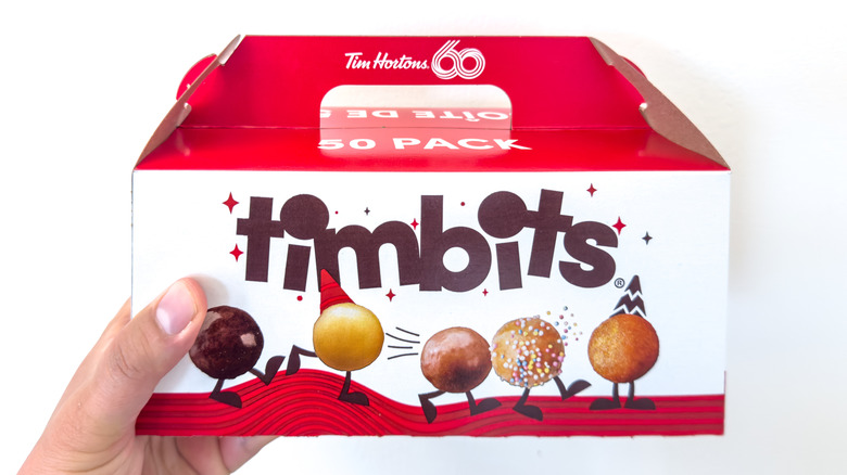 Hand holds box of Timbits against white background