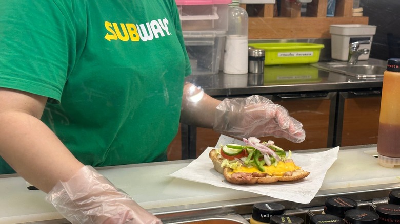 A Subway employee making a sandwich