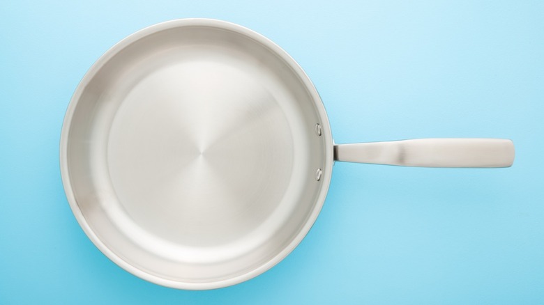 stainless steel frying pan on light blue background