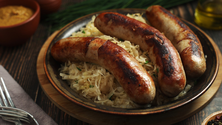 Three bratwurst sausages served with sauerkraut