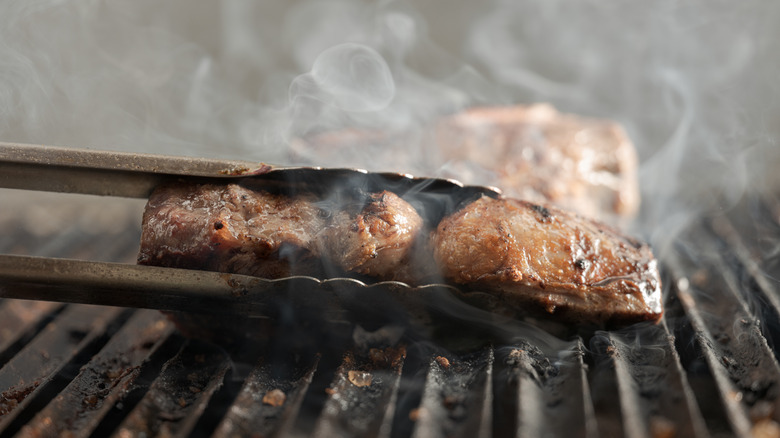 Tongs flipping steak