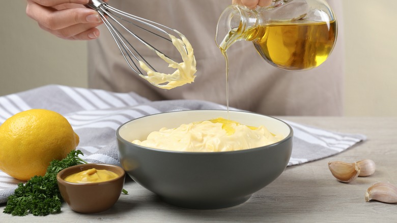 Oil being poured into bowl of mayonnaise 