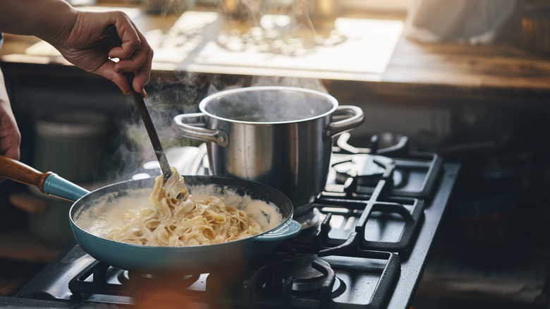 hands cooking fettuccine alfredo