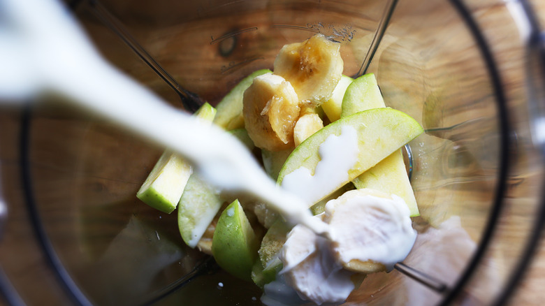 cream pouring into blender with fruit