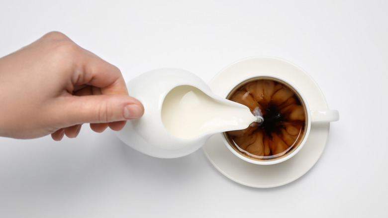 Person pouring coffee creamer