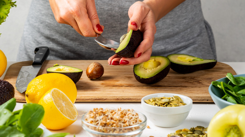 Preparing a dish with avocado, lemon, and seeds