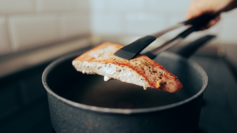 tongs holding cooked fish