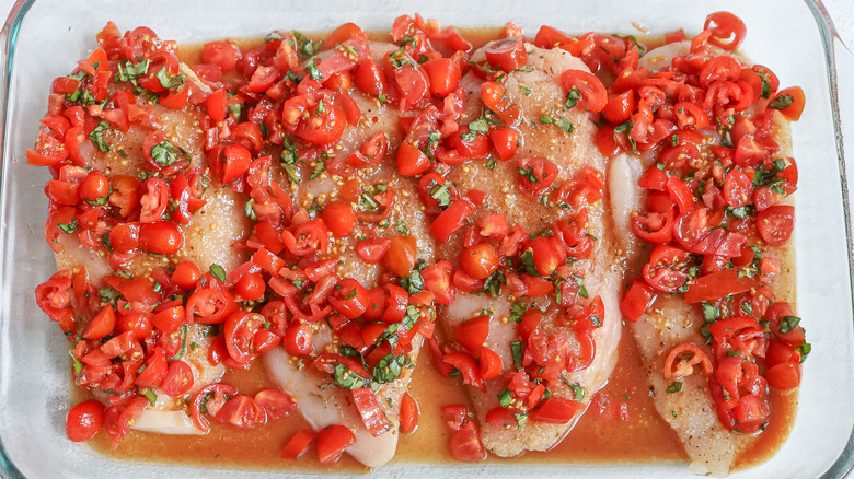 Raw chicken with bruschetta in pan 