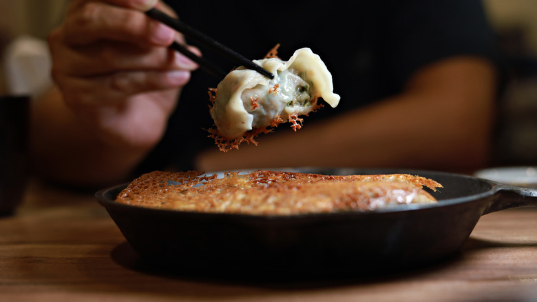 a pair of chopsticks holding a dumpling