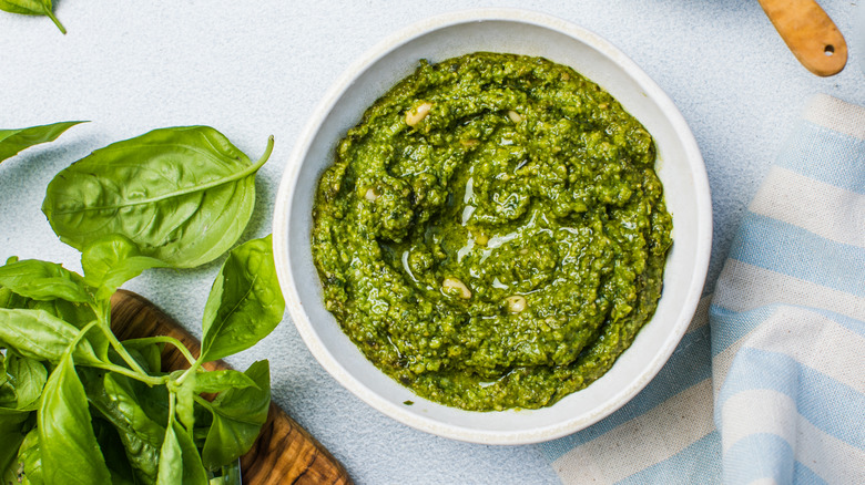 pesto in a white bowl with basil leaves