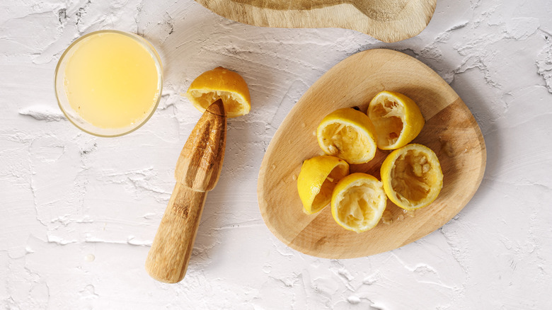 A glass of lemon juice and squeezed lemon halves