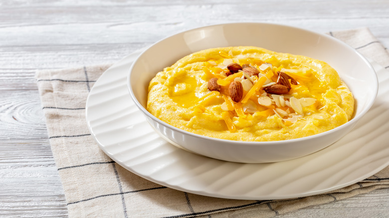 A bowl of corn grits topped with nuts and cheese