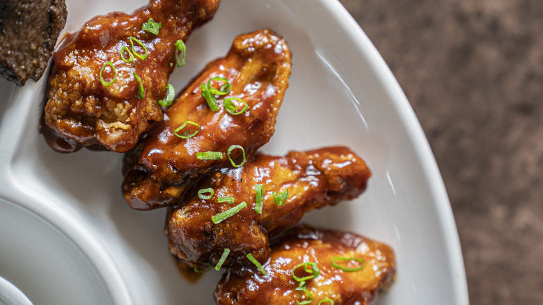 Chicken wings slathered in sticky jelly sauce with green onions