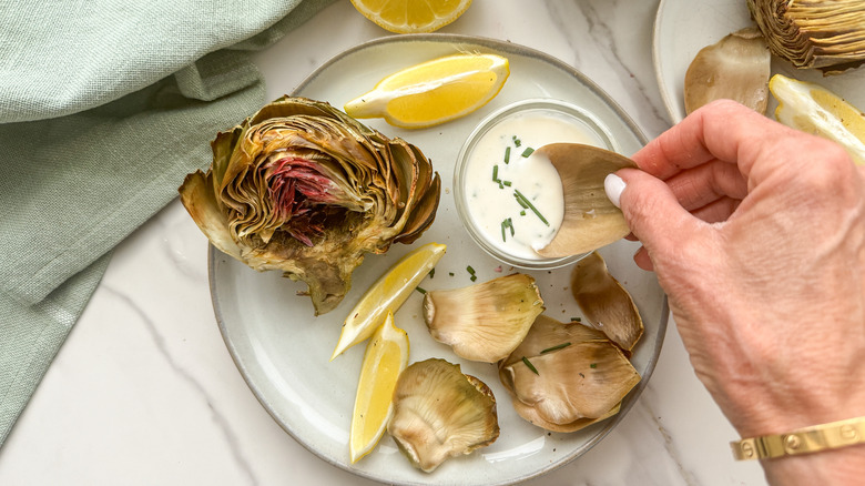 hand dipping leaf in sauce